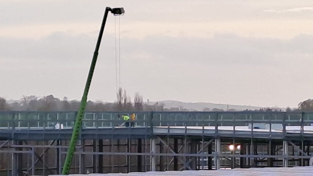 Two workers on construction site with crane.