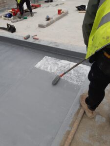 Worker applying waterproof coating on concrete surface