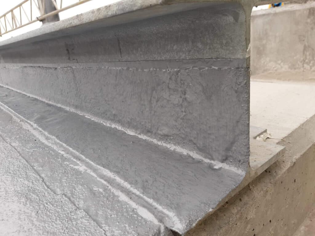 Concrete beam coated with protective grey paint.