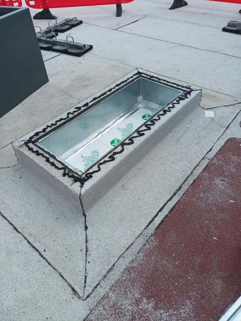 Rooftop skylight with protective edging installation.