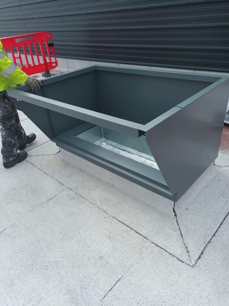 Worker assembling large metal container outdoors
