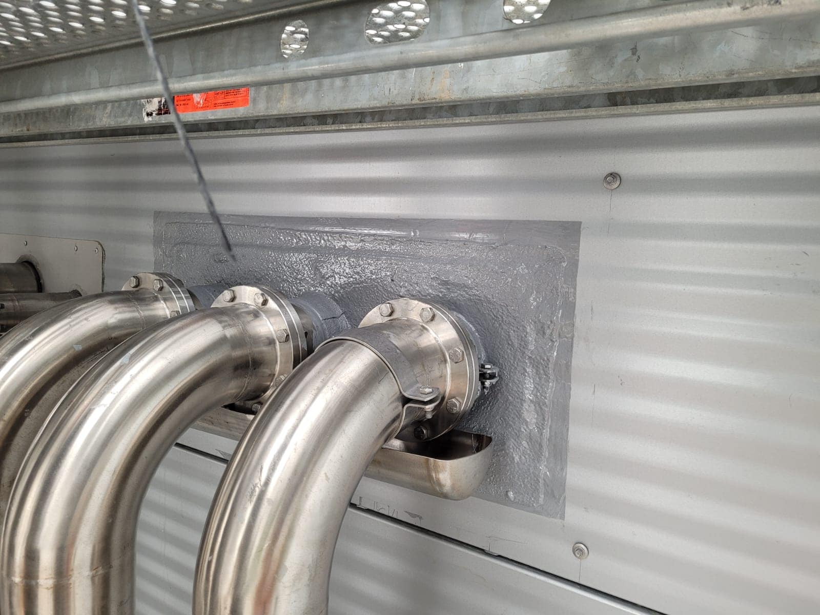 Stainless steel pipes on industrial wall.